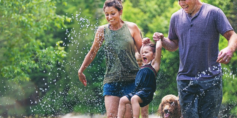 Family running through sprinkler