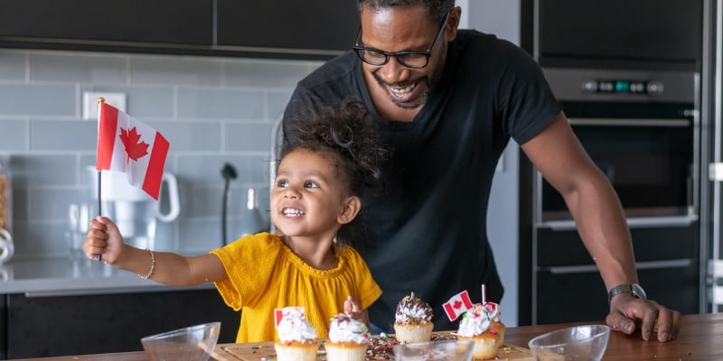 Father and daughter decorate cupcakes for Canada Day.