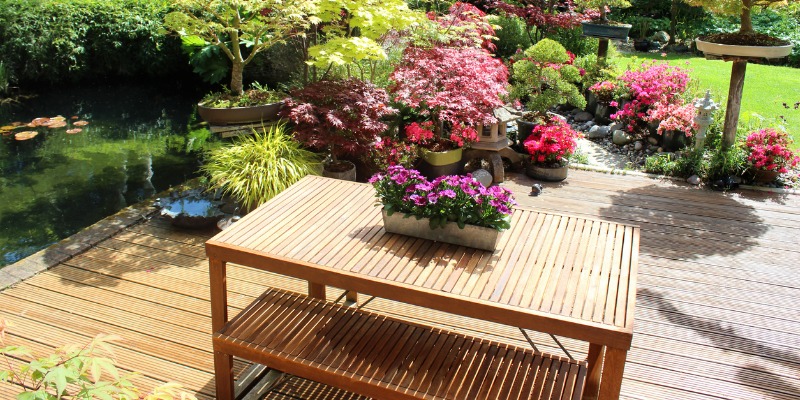 Wooden table on wood deck surrounded by a garden
